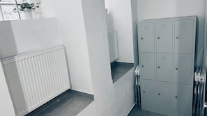 Un couloir avec des casiers, un radiateur et une plante en pot.