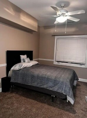 Cozy bedroom with a single bed, ceiling fan, and window with blinds.