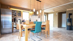 Et moderne køkken med et rustfrit stål køleskab, træskabe og et spiseområde med et bord og stole.