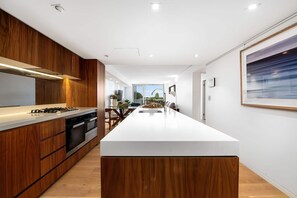A modern kitchen with wooden cabinets, a white countertop, and a large island.