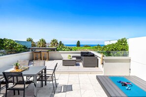 A rooftop terrace with outdoor furniture, a table, and a small pool area.