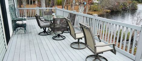 A wooden deck with outdoor furniture, a railing, and a view of a body of water.