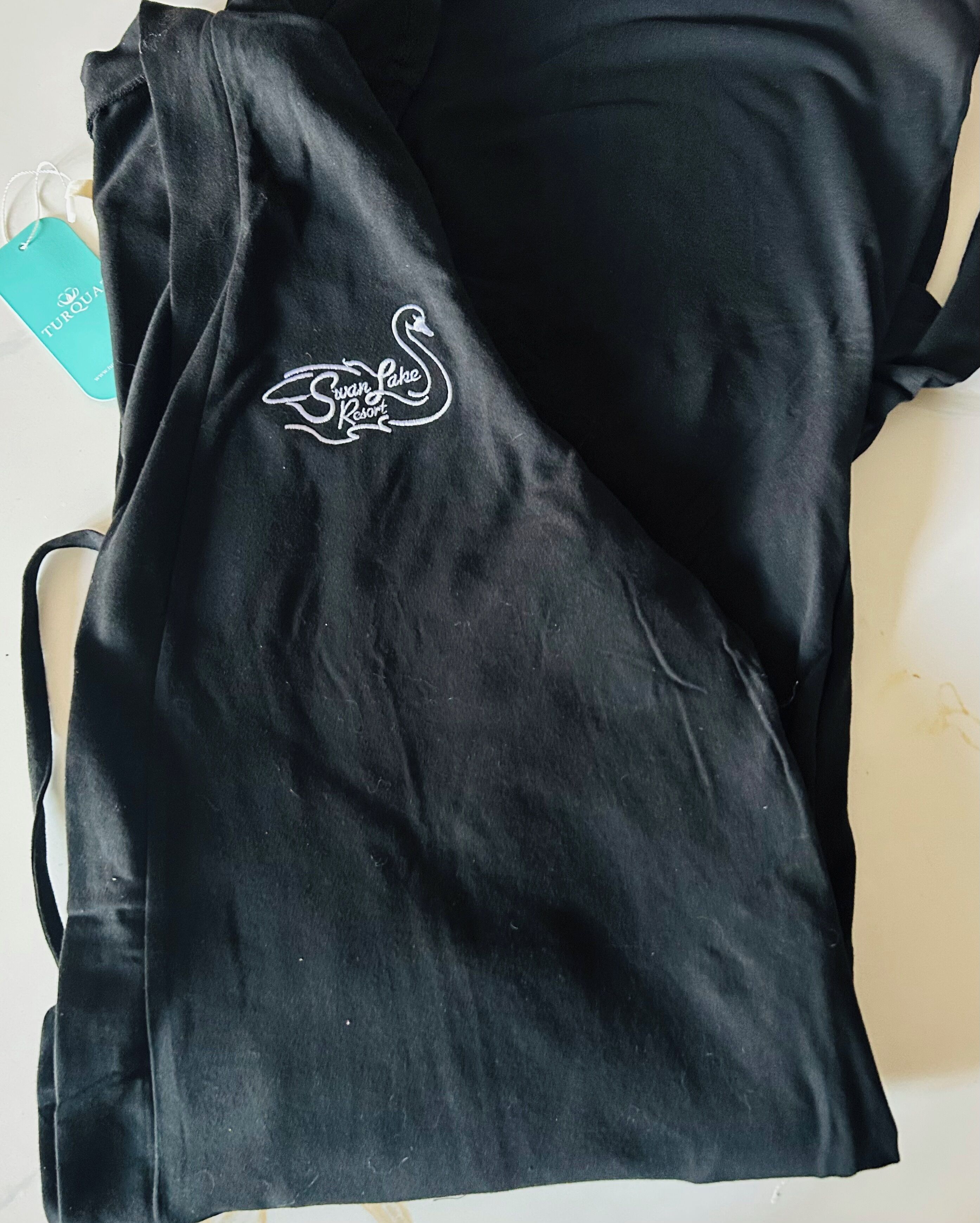 A black t-shirt with a white embroidered logo of Swan Lake Resort.