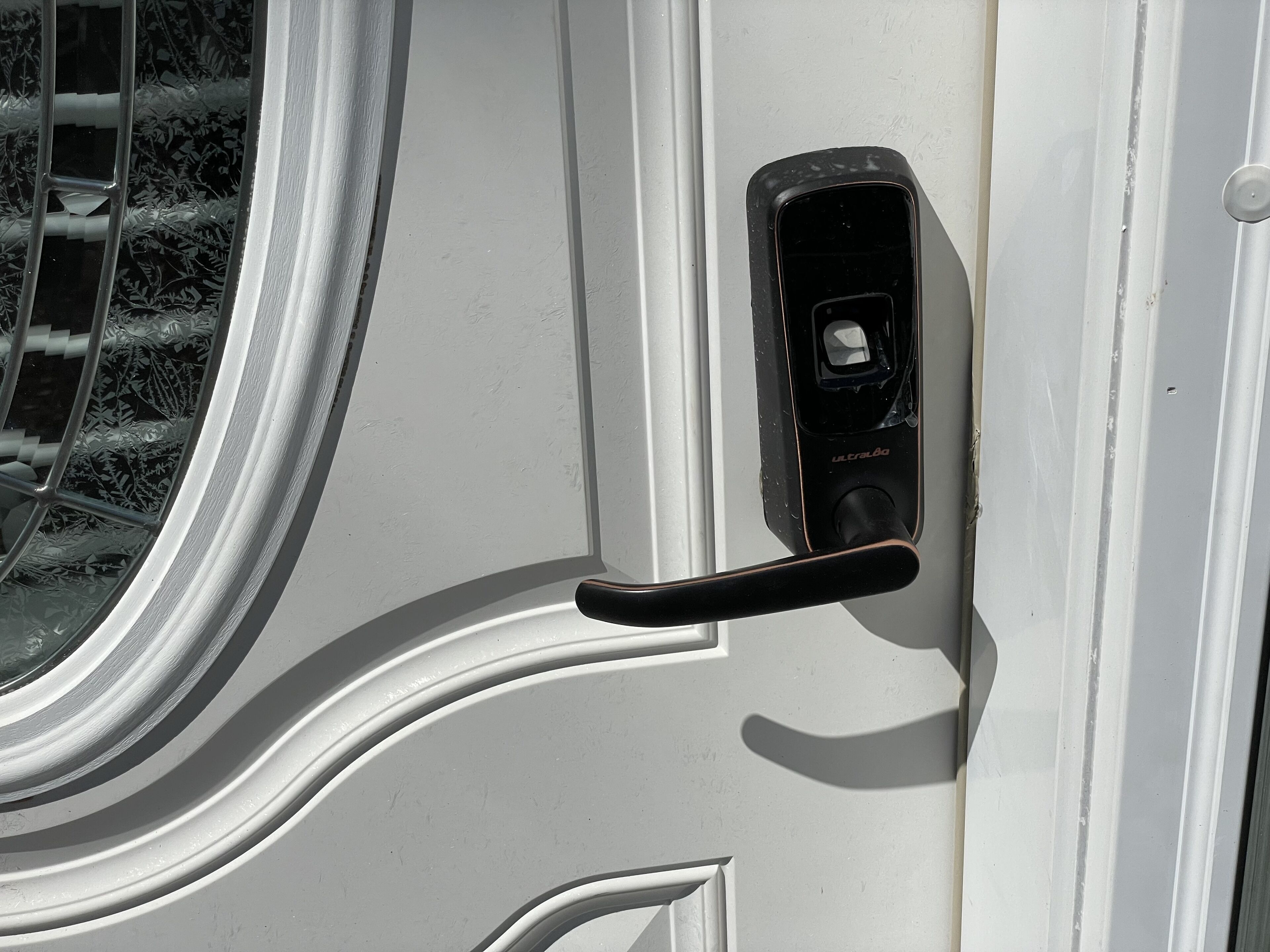 A door with a handle and a keyhole, part of a white exterior wall.