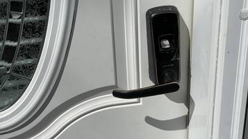 A door with a handle and a keyhole, part of a white exterior wall.