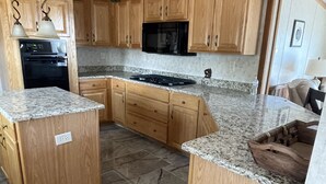A kitchen with wooden cabinets, granite countertops, a built-in oven, and a microwave. - Waterfront Bungalow nightly panoramic view of our illuminated covered Bridge (Galloway)