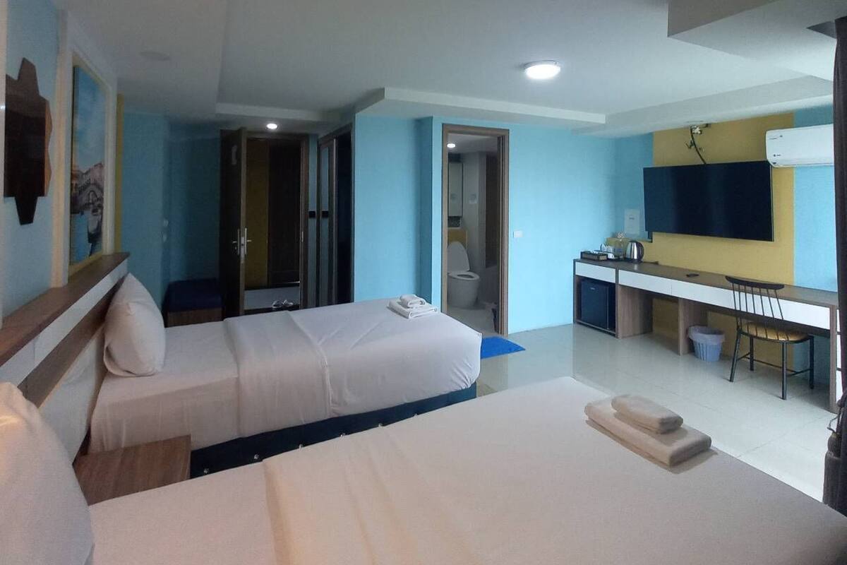 A hotel room with two beds, a desk, a chair, and a TV mounted on the wall.