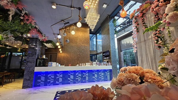 A bar area with a blue-tiled counter, hanging lights, and floral decorations. - BlueTel Re'sidence Bangkok IMPACT (Pak Kret)