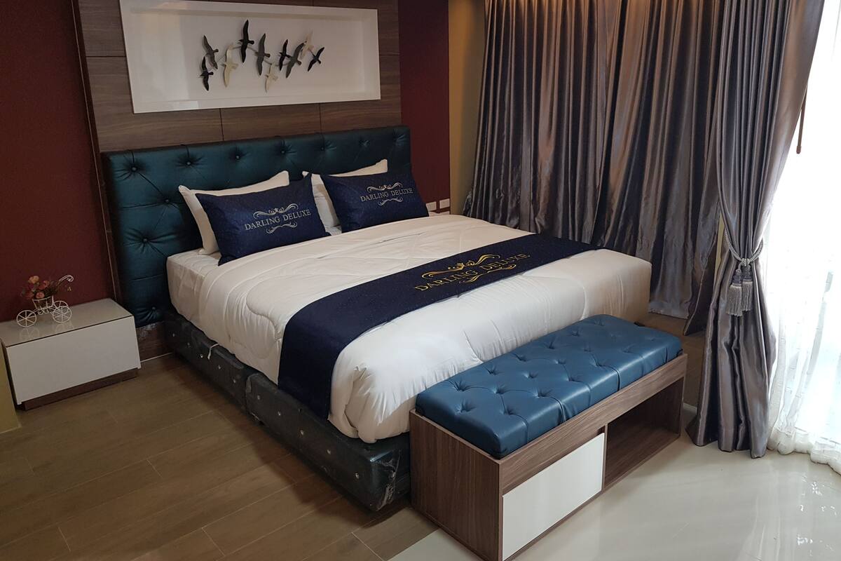 A neatly arranged bedroom with a large bed, a headboard, a bedside table, and a bench.
