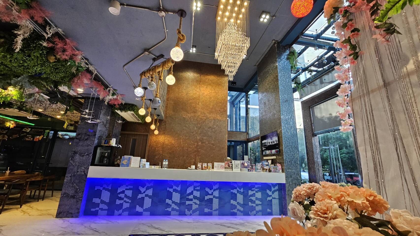A modern interior with a bar area, a reception desk, and a large window offering a view of the outdoors.