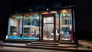 A BlueTel ResidenceE building with large glass windows, a visible entrance, and a sign indicating the establishment is open. - BlueTel Re'sidence Bangkok IMPACT  (Pak Kret)