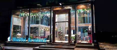 A BlueTel ResidenceE building with large glass windows, a visible entrance, and a sign indicating the establishment is open.