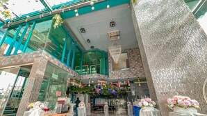 A modern hotel lobby with a glass facade, a reception desk, and a chandelier. - BlueTel Re'sidence Bangkok IMPACT  (Pak Kret)