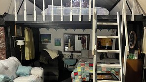 Ein gemütliches, helles Zimmer mit einem Etagenbett, einem Schreibtisch und einer bequemen Sitzecke.