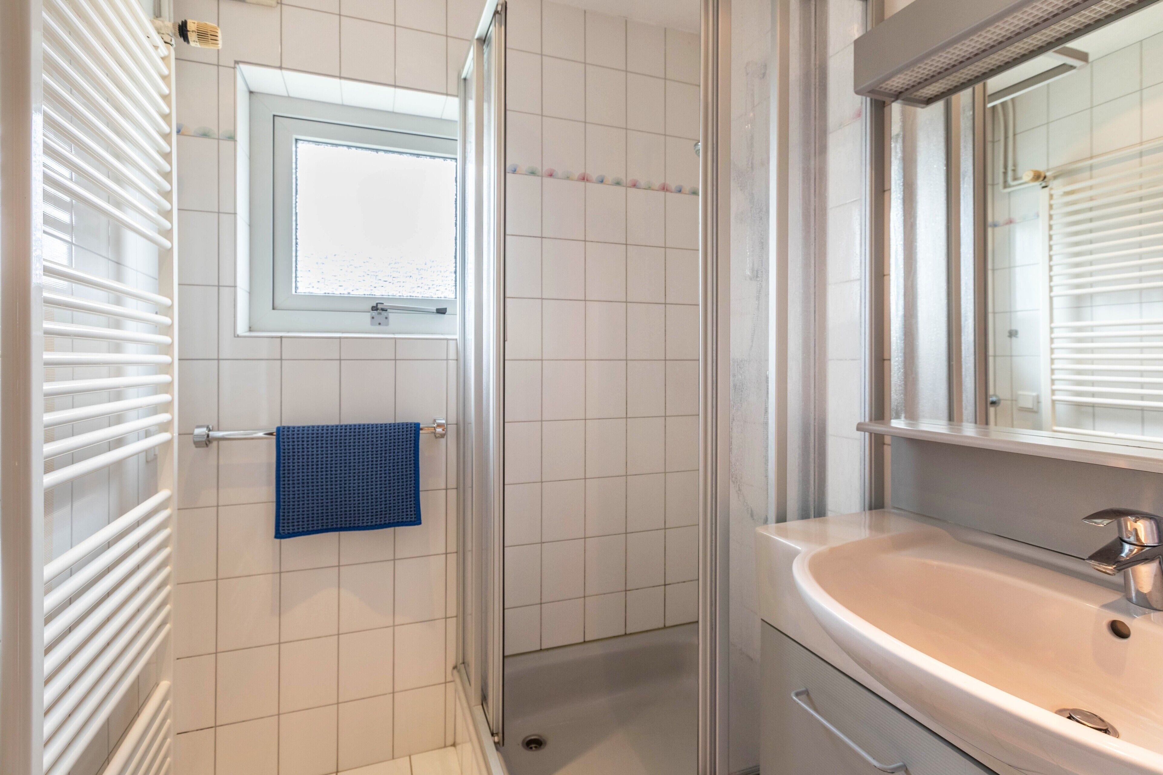 Een badkamer met een wit wastafelmeubel, een spiegel en een douchecabine.