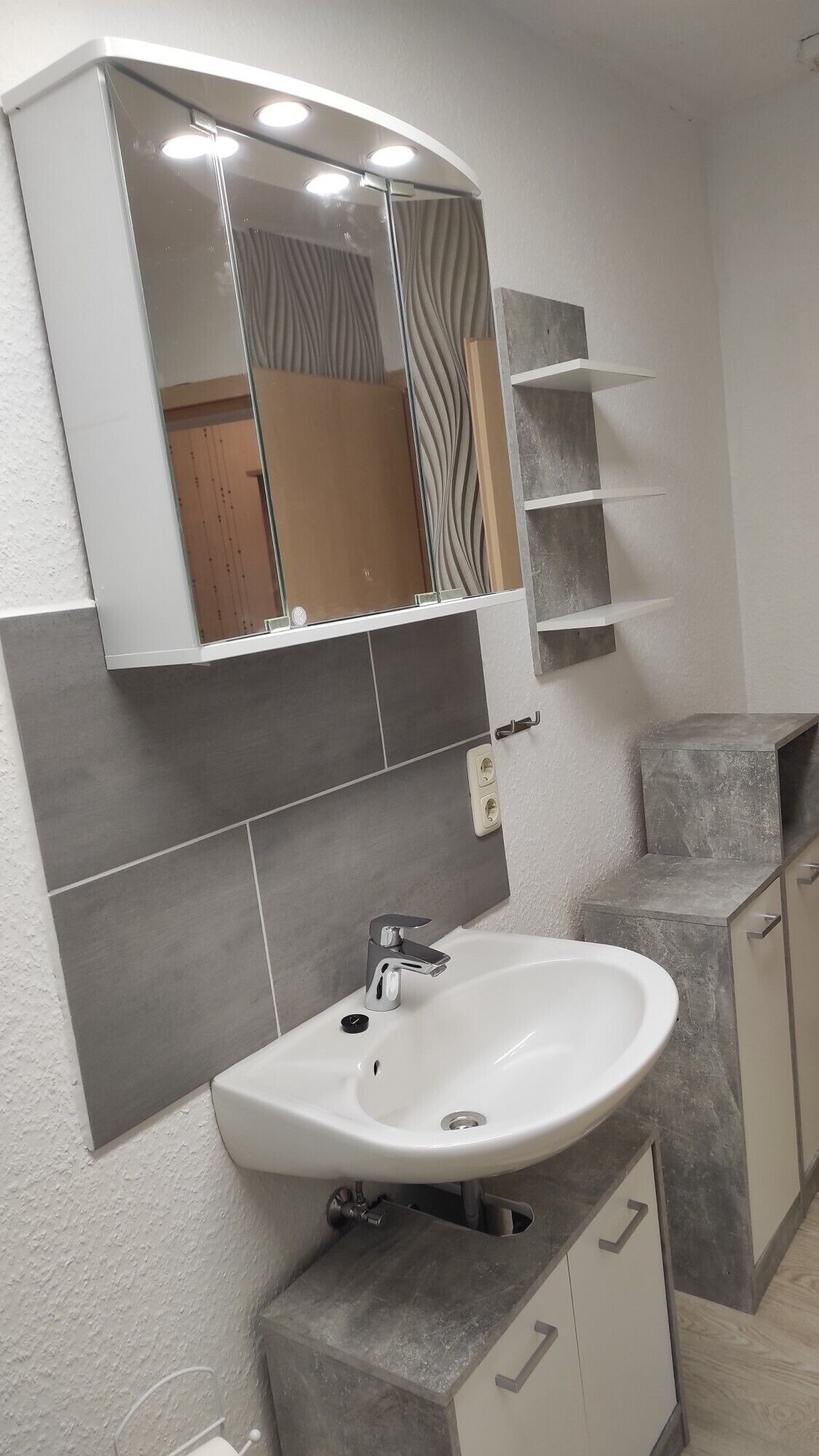 A bathroom with a white sink, a mirror, and a vanity with a mirror above it.