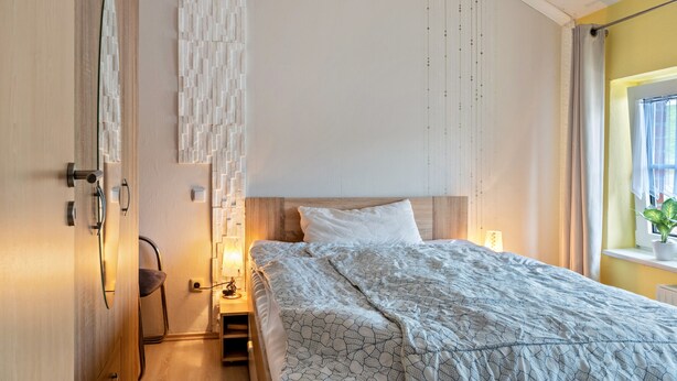 Una camera da letto con un letto, un comodino, una sedia, un armadio e una finestra con tende.