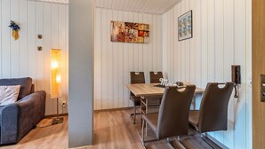 Une pièce moderne avec une table à manger en bois, quatre chaises, un canapé, une lampe et un tableau au mur.