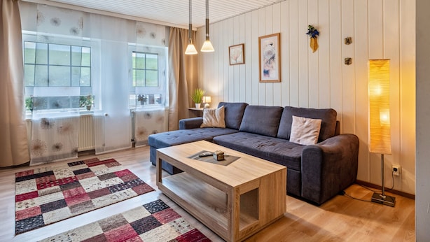 Un salon moderne avec un canapé, une table basse et une lampe.