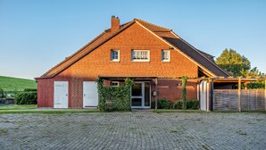 Une maison en briques avec un toit en pente, un garage et une allée pavée.