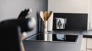 Eine moderne Küche mit einer Edelstahl-Dunstabzugshaube, einem Holz-Küchenhelferhalter und einer schwarzen Arbeitsplatte.