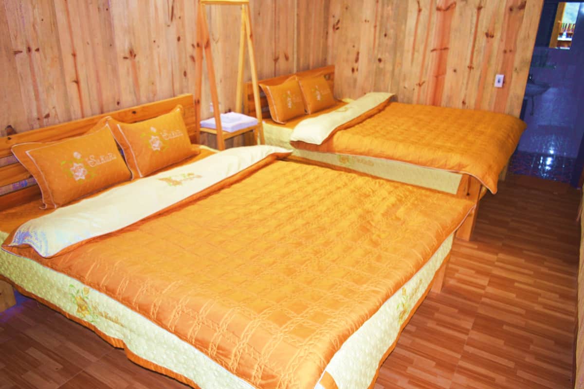 Een kamer met twee bedden, houten wanden en een houten vloer.