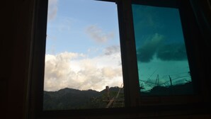 Une fenêtre donnant sur une chaîne de montagnes et un ciel partiellement nuageux.