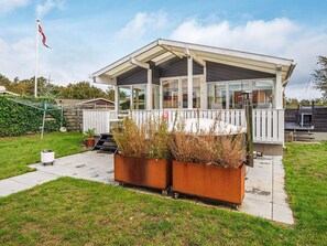 A modern outdoor structure with a covered patio, a white fence, and a flagpole.