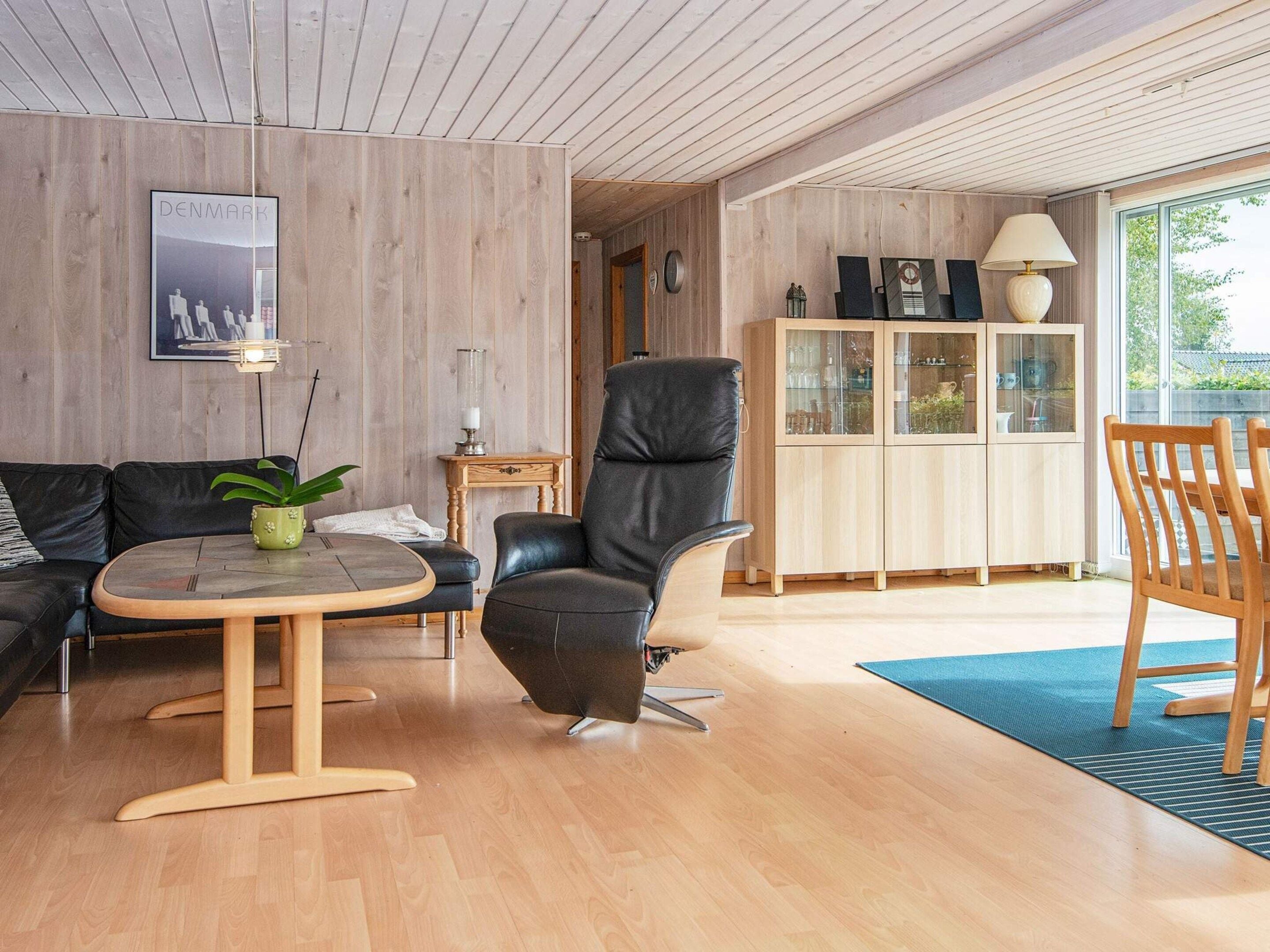 A modern living room with a leather sofa, a black leather chair, a wooden coffee table, and a cabinet with glass doors.