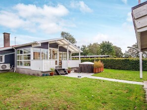 A modern house with a covered patio, a visible air conditioning unit, and a well-maintained lawn.