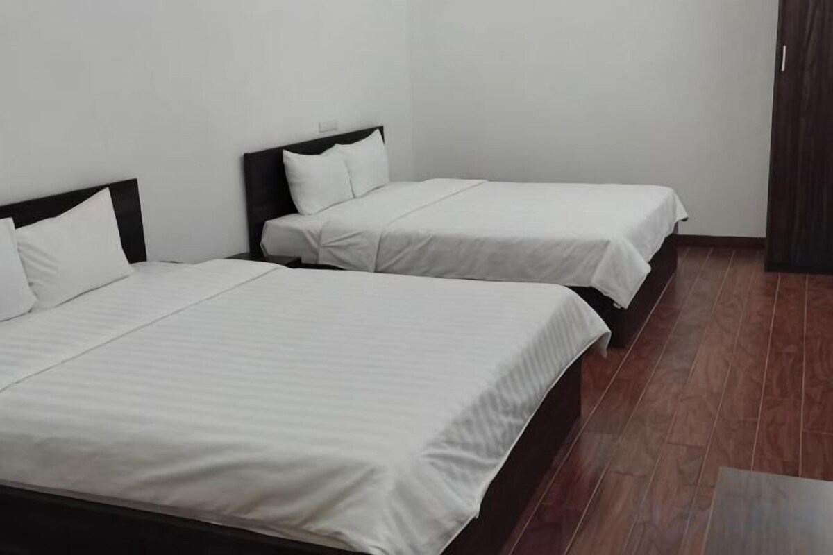 Una habitación con dos camas individuales, cada una con cabecero de madera y ropa de cama blanca.