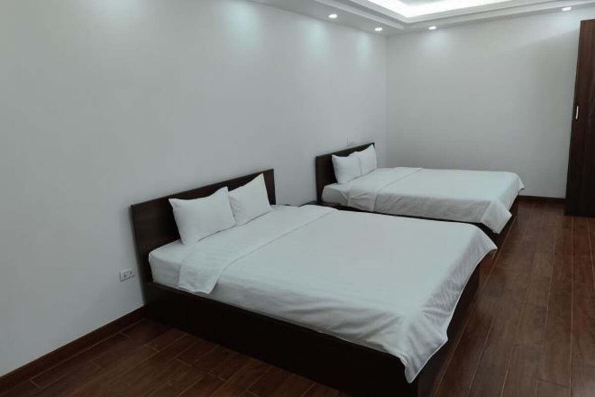 Een hotelkamer met twee bedden, een houten vloer en een dakvenster.