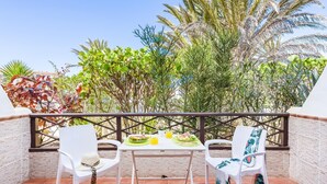 A balcony with two white chairs, a table with a green placemat, and a glass of orange juice. - 9 Amarilla Bay Holiday Pool Terrace (Costa del Silencio)
