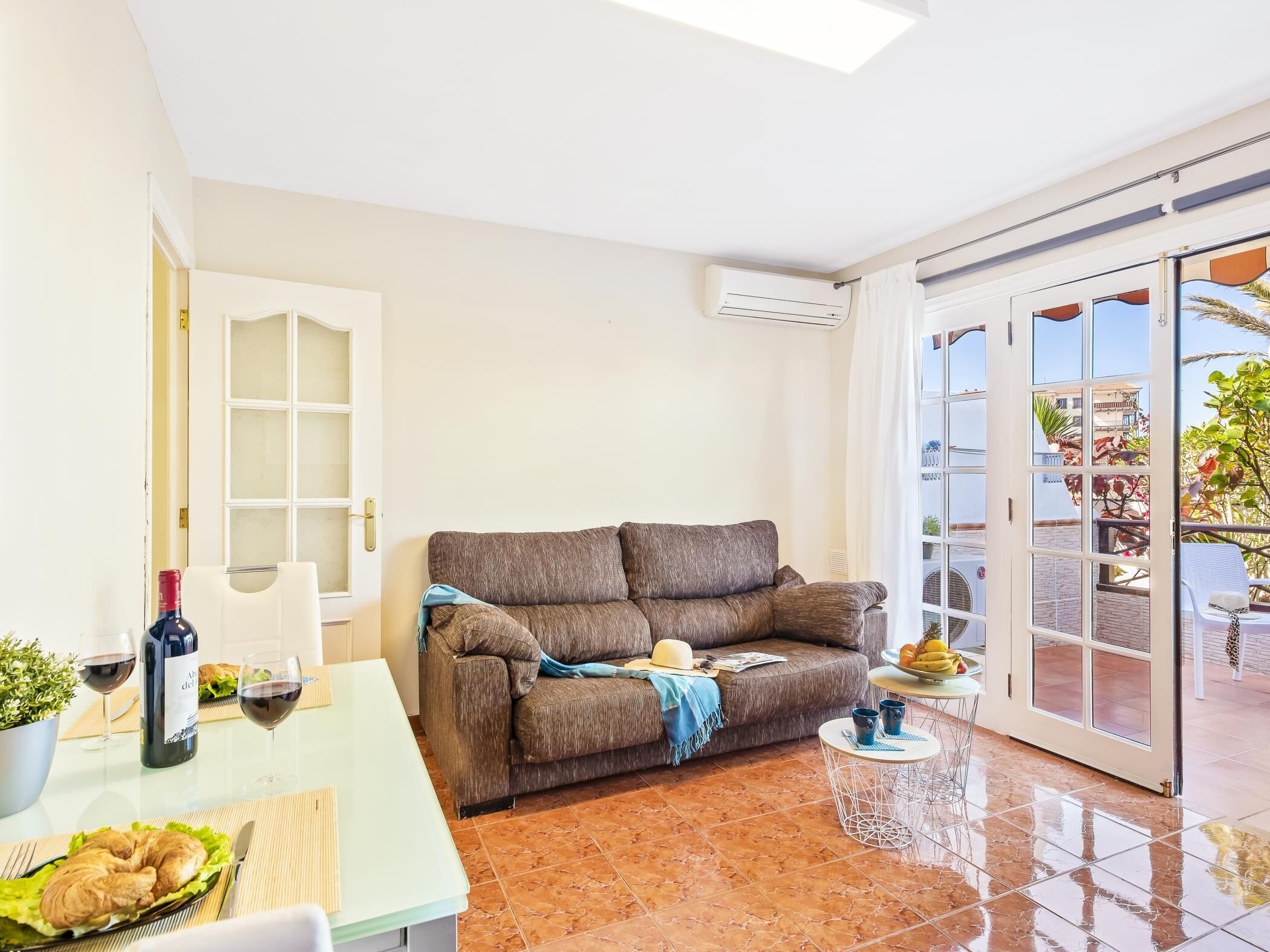 Una sala de estar acogedora con un sofá, una mesa de comedor con un croissant, copas de vino y una botella.