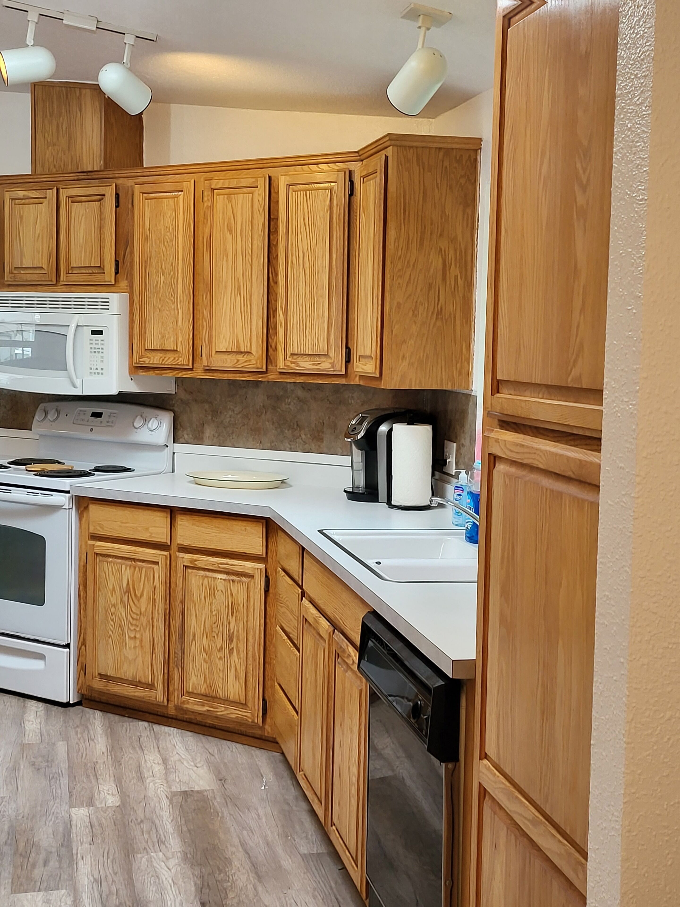 A kitchen with wooden cabinets, a microwave, stove, and dishwasher.