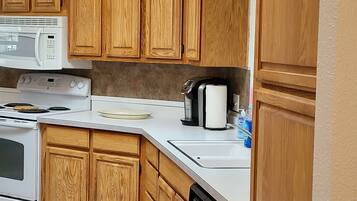 A kitchen with wooden cabinets, a microwave, stove, and dishwasher.