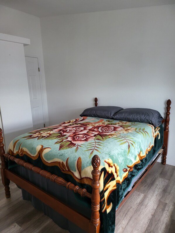 A bed with a floral bedspread, a wooden headboard, and a white door in the background.