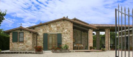A stone house with a gravel driveway and a covered patio area.