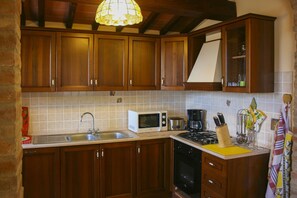 A kitchen with wooden cabinets, a microwave, a sink, and a stove.