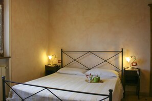 A single bed with a metal frame, two bedside tables with lamps, and a bedside table with a tray of items. - 8 people villa with private pool and garden, situated near Castiglione del Lago. One of the ground f (Castiglione del Lago)