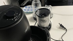 A kitchen with a coffee maker, a kettle, and a pot on the stove.