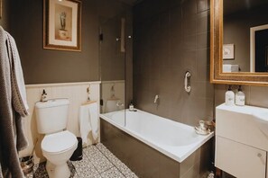 Une salle de bain avec une baignoire blanche, des toilettes et un espace douche.