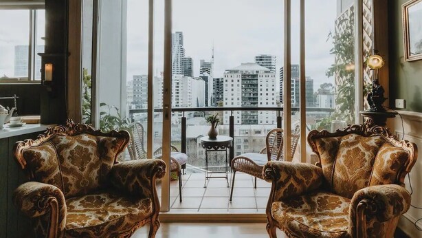 A room with two ornate chairs facing a balcony with a city view. - Boutique central apartment|private balcony|parking (Docklands)