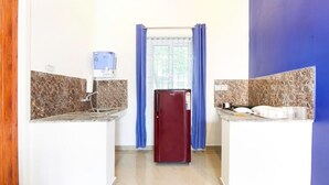 Una cocina compacta con encimeras de granito, un refrigerador y una ventana con cortinas azules.