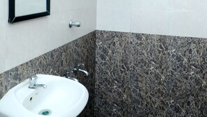 Un baño con lavamanos blanco, un espejo, un perchero para toallas y un calentador de pared.
