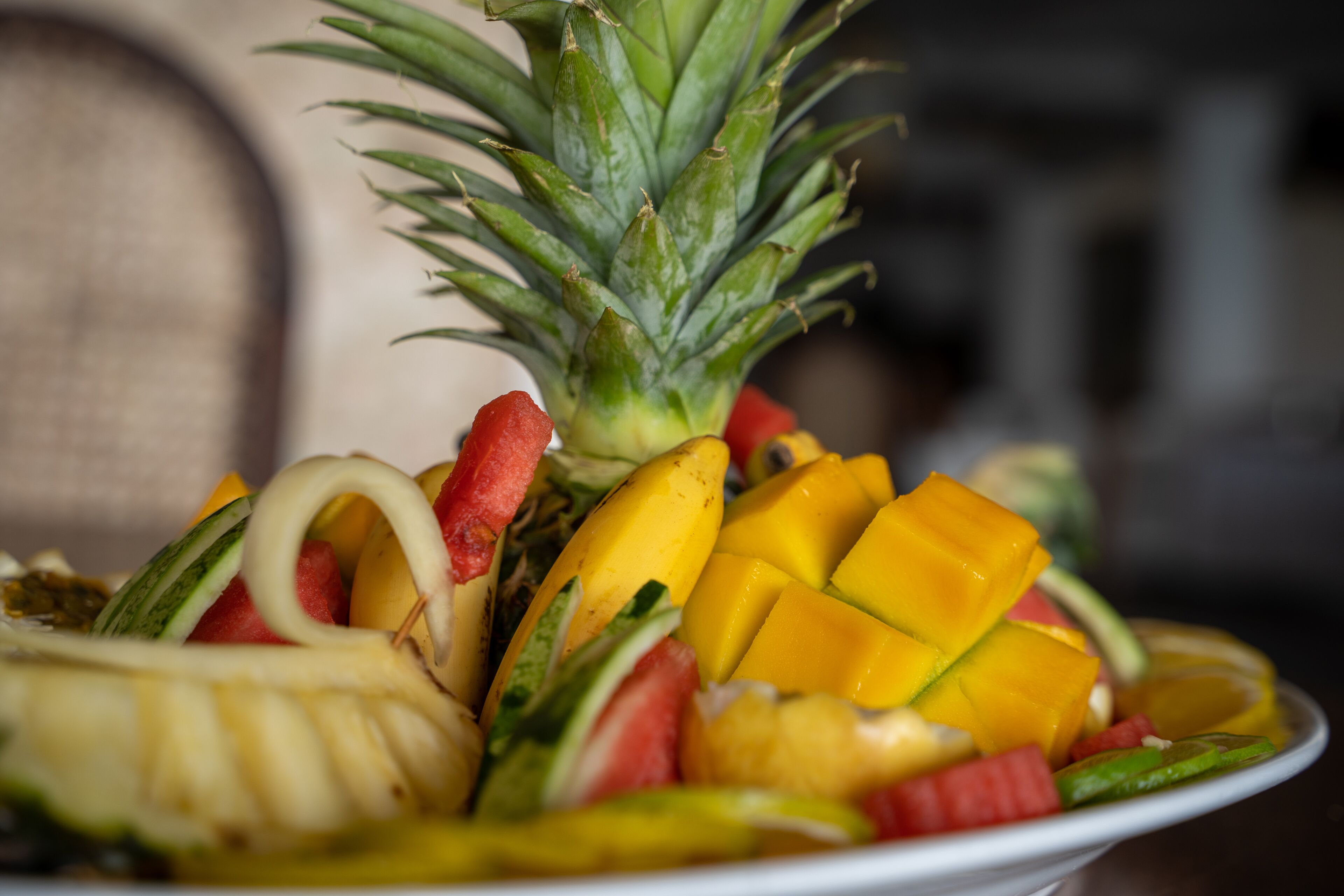 A bowl of assorted fruits including pineapple, mango, watermelon, and banana.