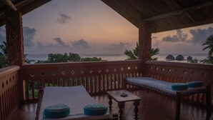 Een overdekt terras met uitzicht op zee bij zonsondergang.