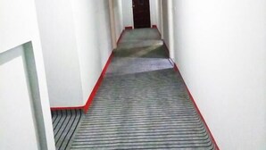 Un long couloir étroit aux murs blancs et au tapis à rayures.
