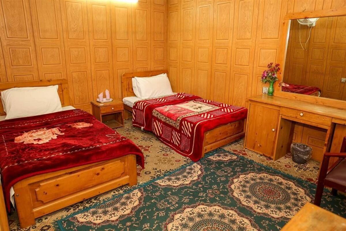 Una habitación con dos camas de madera, un aparador de madera y un espejo.