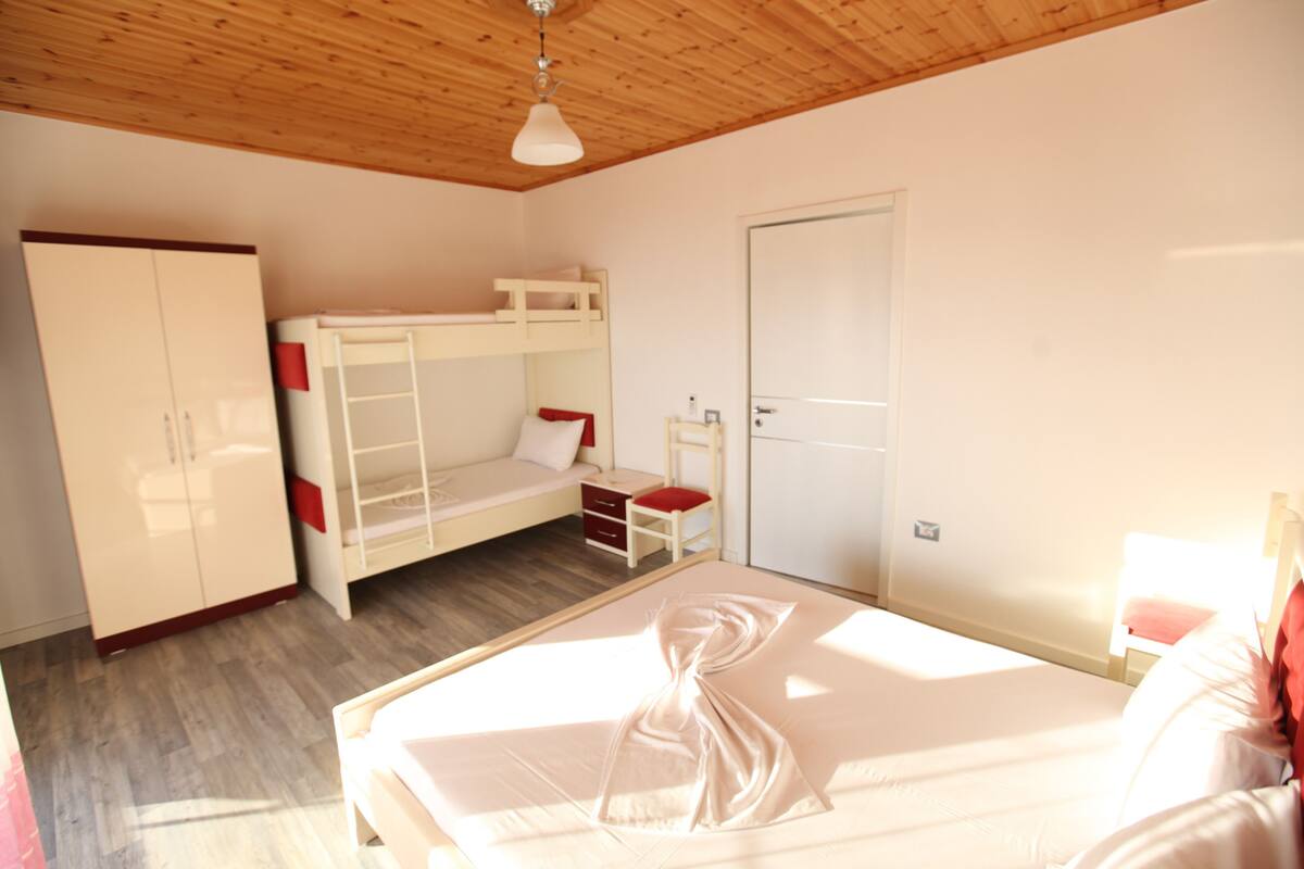 Un dormitorio con literas, un armario, un escritorio y una puerta.